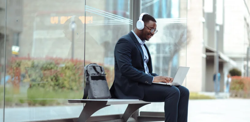 Man using laptop while waiting at bus stop