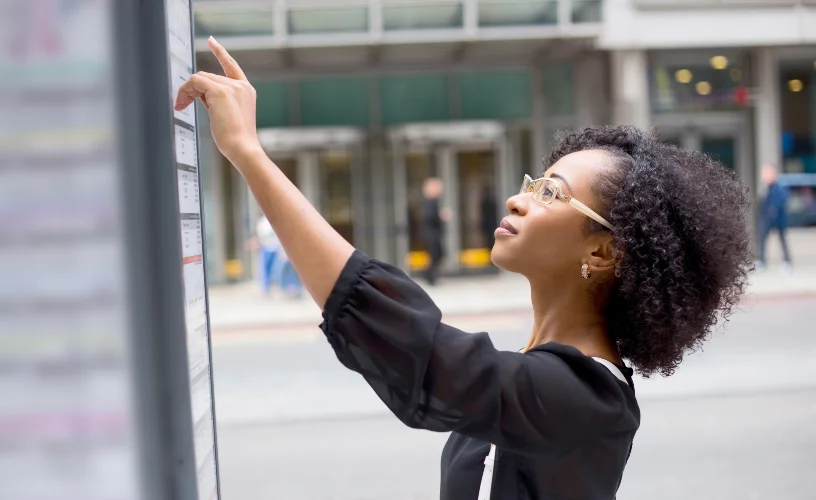 Woman looking at roadside bus timetable